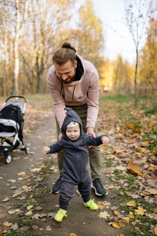 a woman standing next to a baby in a stroller, by Jaakko Mattila, pexels contest winner, handsome man, in fall, walking at the park, thumbnail