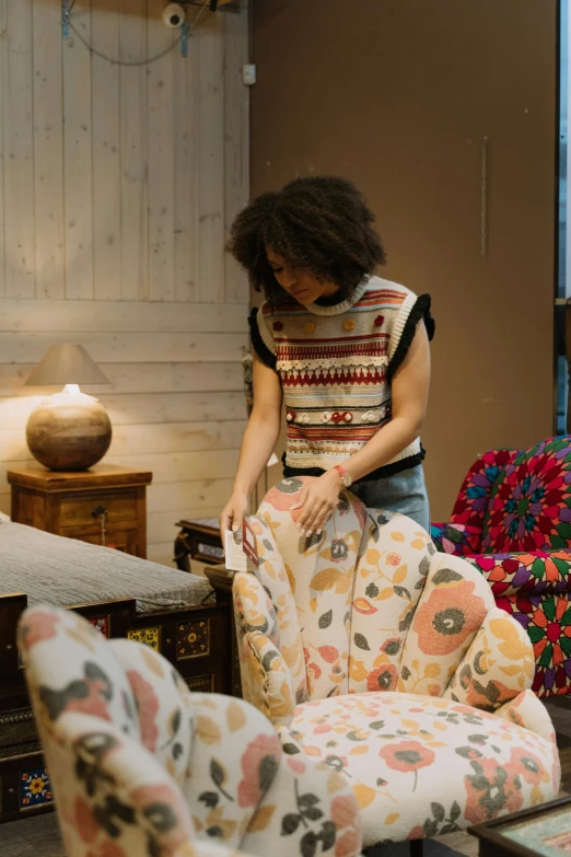 a woman standing next to a couch in a living room, process art, patterned clothing, merchants, cozy arm chairs, production photo