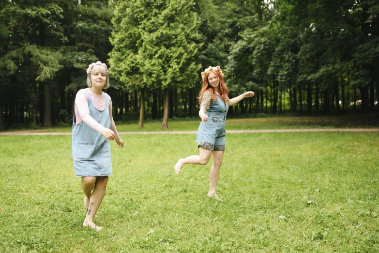 a couple of women standing on top of a lush green field, an album cover, pexels, blue overalls, young redhead girl in motion, around tree babies running, playing games