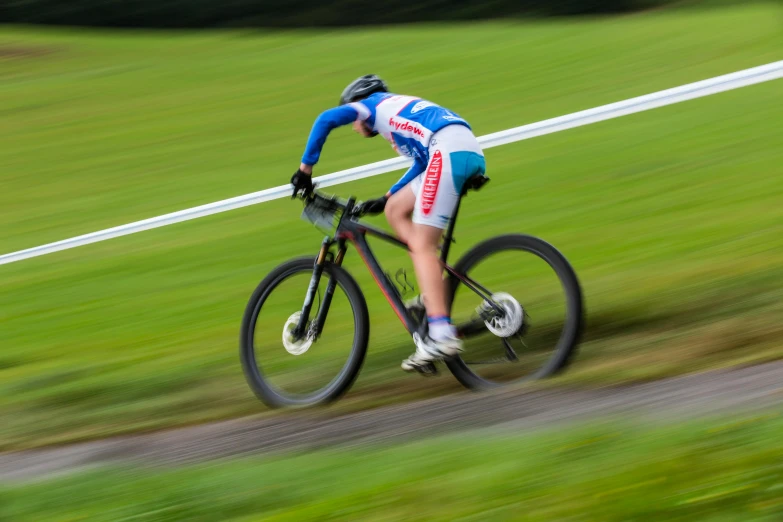 a man riding a bike on top of a grass covered field, in a race competition, profile image, high-speed sports photography, lighting her with a rim light