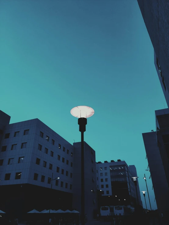 a street light sitting in the middle of a city, inspired by Elsa Bleda, unsplash contest winner, postminimalism, teal sky, low quality photo, in a square, hospital lighting