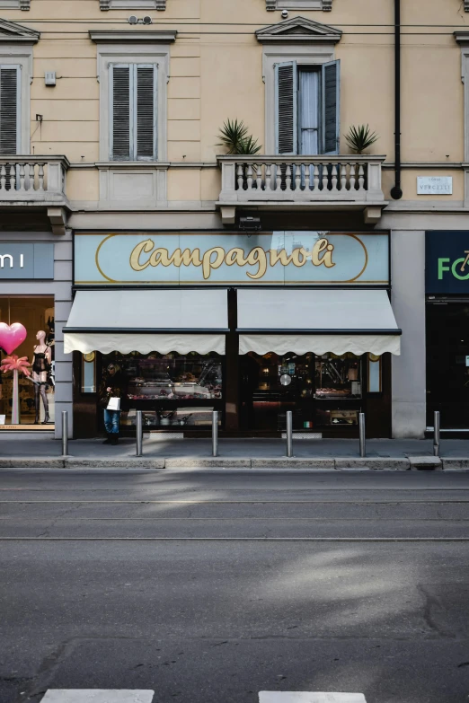 a couple of people crossing a street in front of a store, inspired by Giuseppe Camuncoli, bright signage, champagne, seen from afar, a middle-shot from front