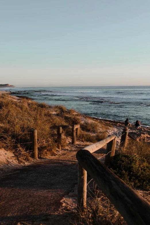 a path leading to a beach next to the ocean, lachlan bailey, warm light, afternoon hangout, f / 2 0