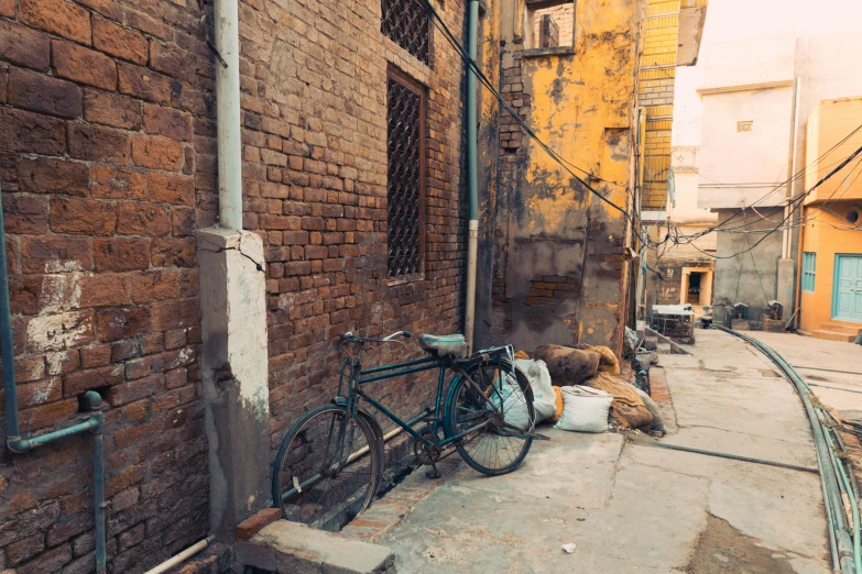 a bicycle parked on the side of a brick building, pexels contest winner, bengal school of art, junk on the ground, narrow streets, background image