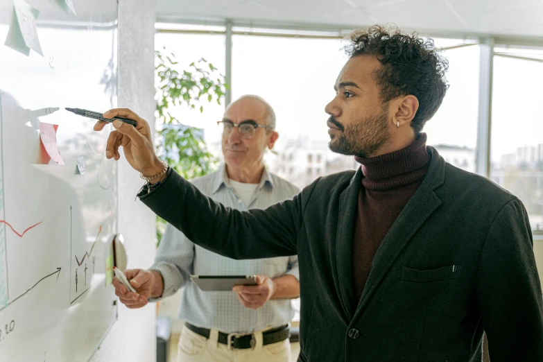 a man writing on a white board while another man looks on, by Carey Morris, pexels contest winner, mc escher and ronny khalil, pointing, in the office, older male