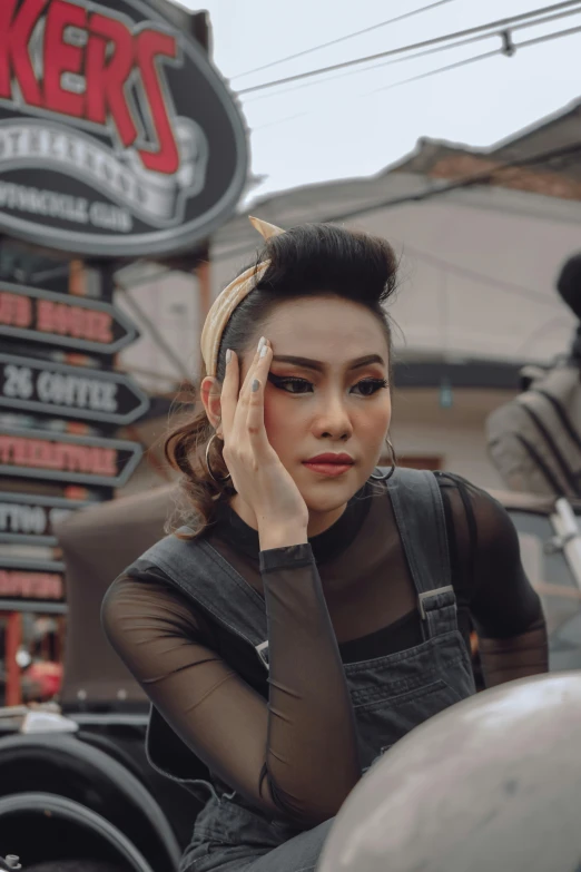 a woman sitting on the back of a motorcycle, inspired by Rudy Siswanto, trending on pexels, lowbrow, traditional makeup, androgynous face, square, retro style ”