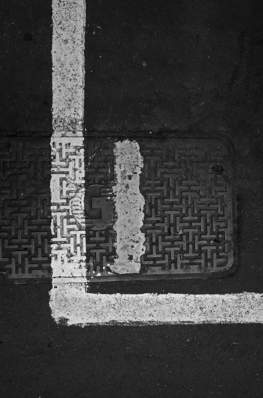 a black and white photo of a manhole cover, an album cover, auto-destructive art, square lines, ( ( photograph ) ), traffic, 1 9 8 5