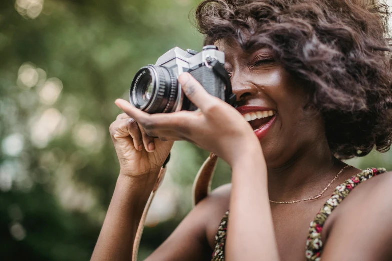 a woman taking a picture with a camera, pexels contest winner, afrofuturism, making the best smug smile, half image, african american woman, colour photograph