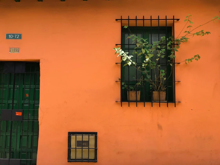 an orange building with a green door and window, inspired by Ceferí Olivé, pexels contest winner, tlaquepaque, black windows, a green, colombian