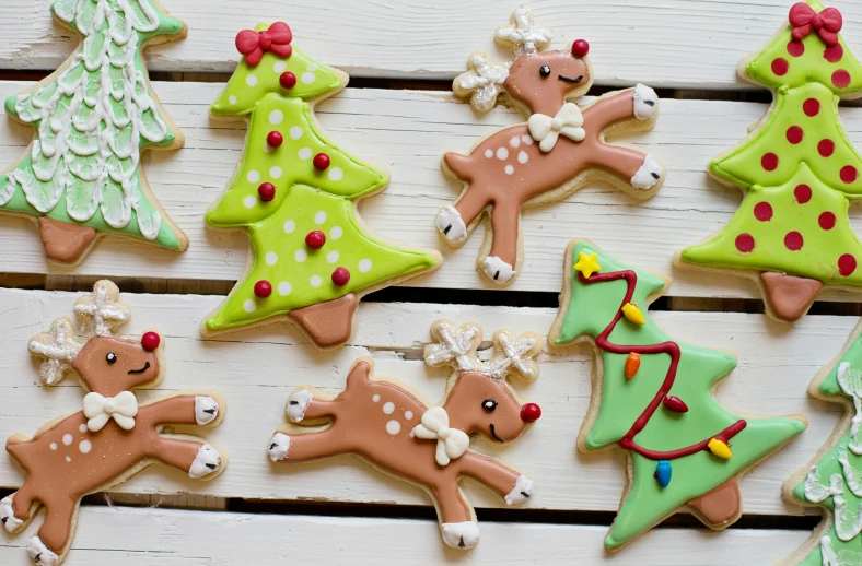 a number of decorated christmas cookies on a table, a cartoon, by Julia Pishtar, pexels, leaping from babaob tree, bows, close up shot from the side, wide high angle view