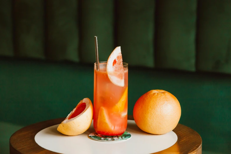 a drink sitting on top of a table next to a grapefruit, press shot, cocktail bar, multiple stories, thumbnail