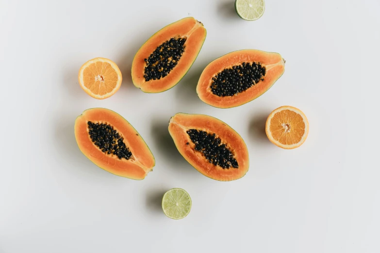 oranges, limes, and papanas on a white surface, by Carey Morris, trending on pexels, gestation inside a watermelon, black and orange, seeds, (light orange mist)