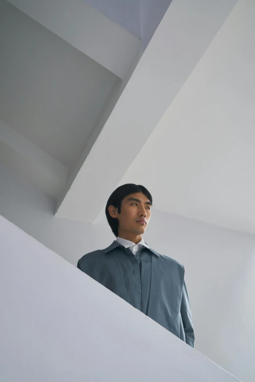 a man standing at the top of a staircase, an album cover, inspired by Fei Danxu, grey turtleneck coat, ignant, wearing a blue robe, qichao wang