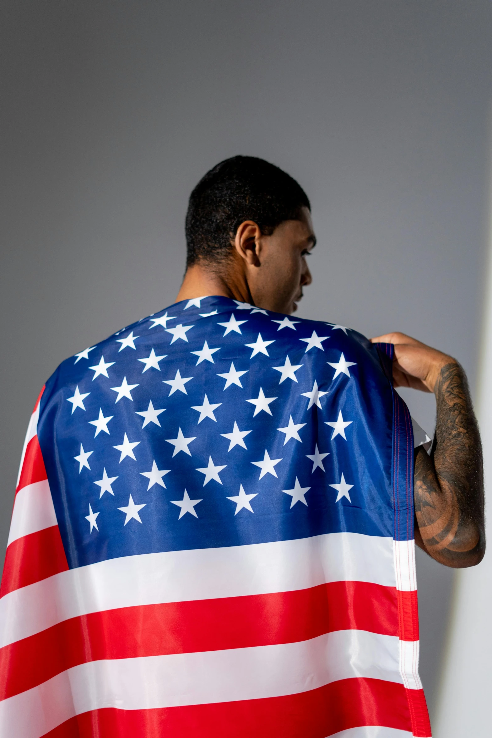 a man holding an american flag draped over his shoulders, inspired by Frank Mason, wearing basketball jersey, zoomed in, product shot, luis melo