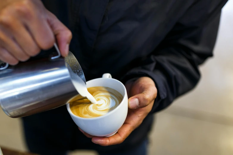 a person pouring milk into a cup of coffee, by Niko Henrichon, trending on unsplash, aussie baristas, award-winning crisp details”, 9 9 designs, calm weather