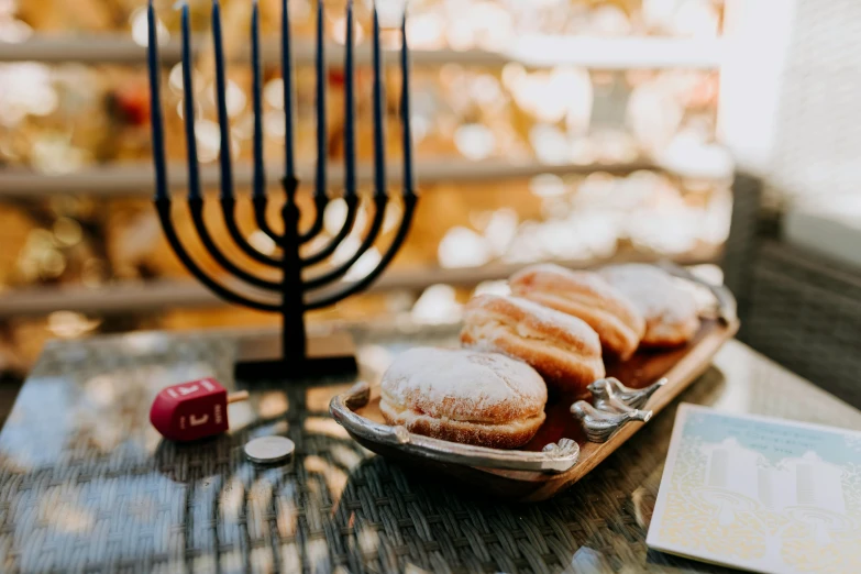 a plate of doughnuts and a menorah on a table, by Julia Pishtar, trending on unsplash, fan favorite, shrines, square, sukkot