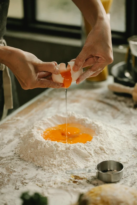 a close up of a person preparing food on a table, covered in white flour, raw egg yolks, fan favorite, in house