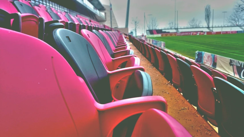 a row of red chairs sitting in front of a soccer field, inspired by Lee Gatch, pexels contest winner, pink and black, view, soft vinyl, thumbnail