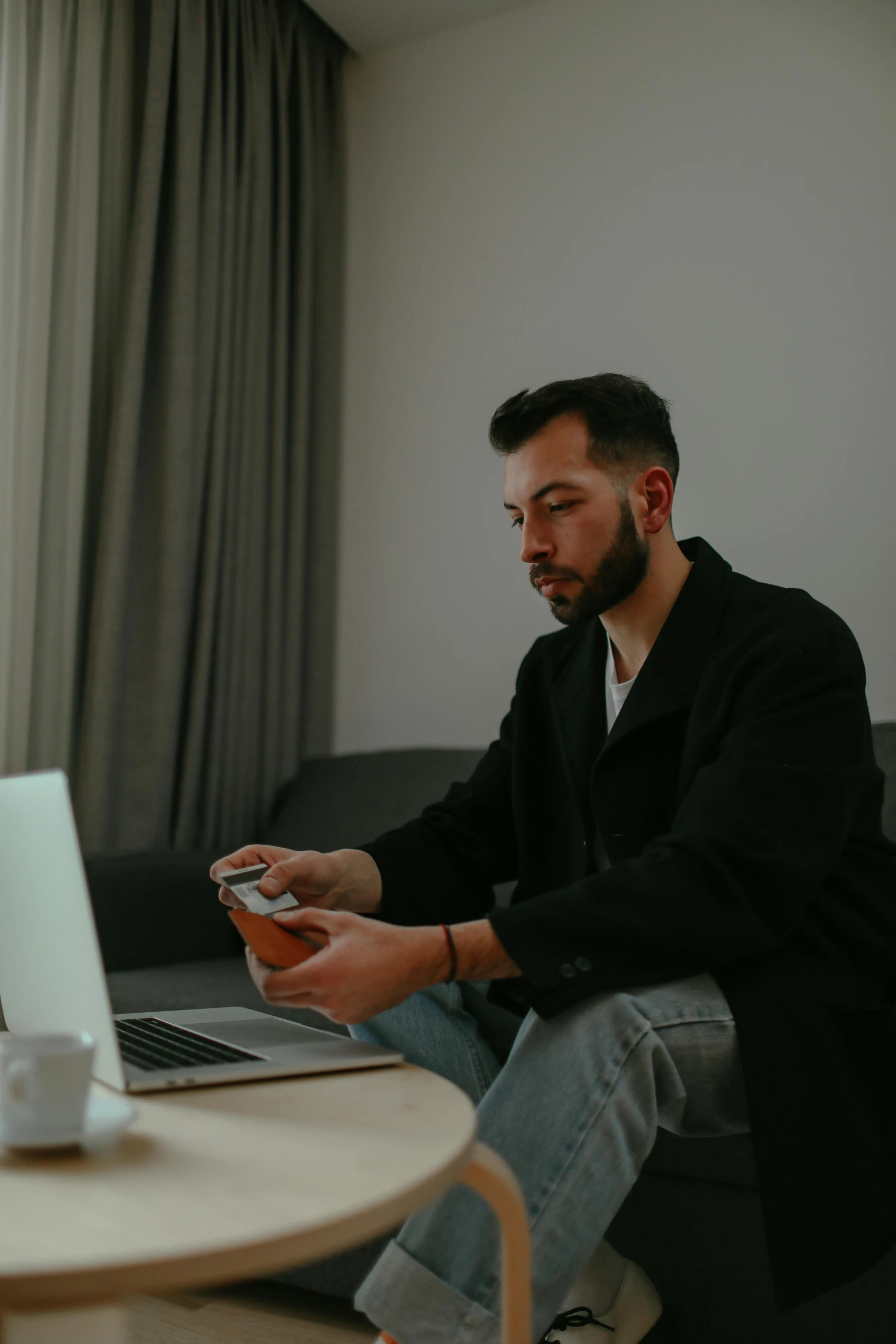 a man sitting on a couch in front of a laptop, by Sebastian Vrancx, pexels contest winner, wearing business casual dress, looking at his phone, looking serious, link from zelda using computer