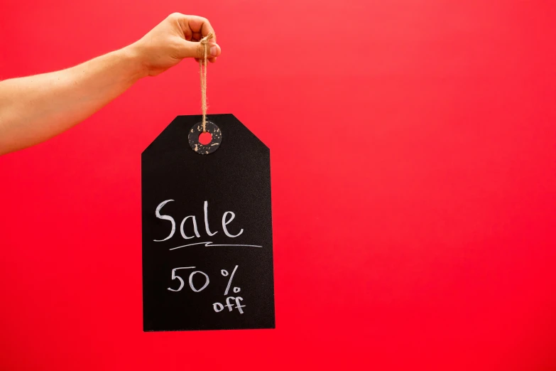 a hand holding a sale tag on a red background, pexels, blackboard, 50, photoshoot, bl