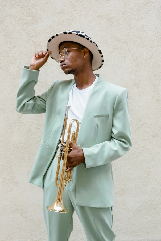 a man in a suit and hat holding a trumpet, inspired by Barthélemy Menn, trending on pexels, harlem renaissance, sea - green and white clothes, tall thin, model posing, california