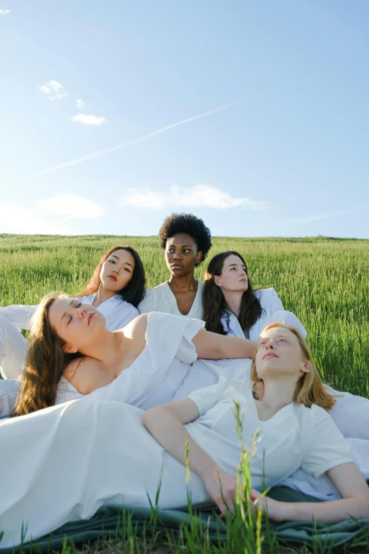 a group of women laying on a blanket in a field, inspired by Vanessa Beecroft, unsplash, renaissance, white shirts, sky, ignant, skincare