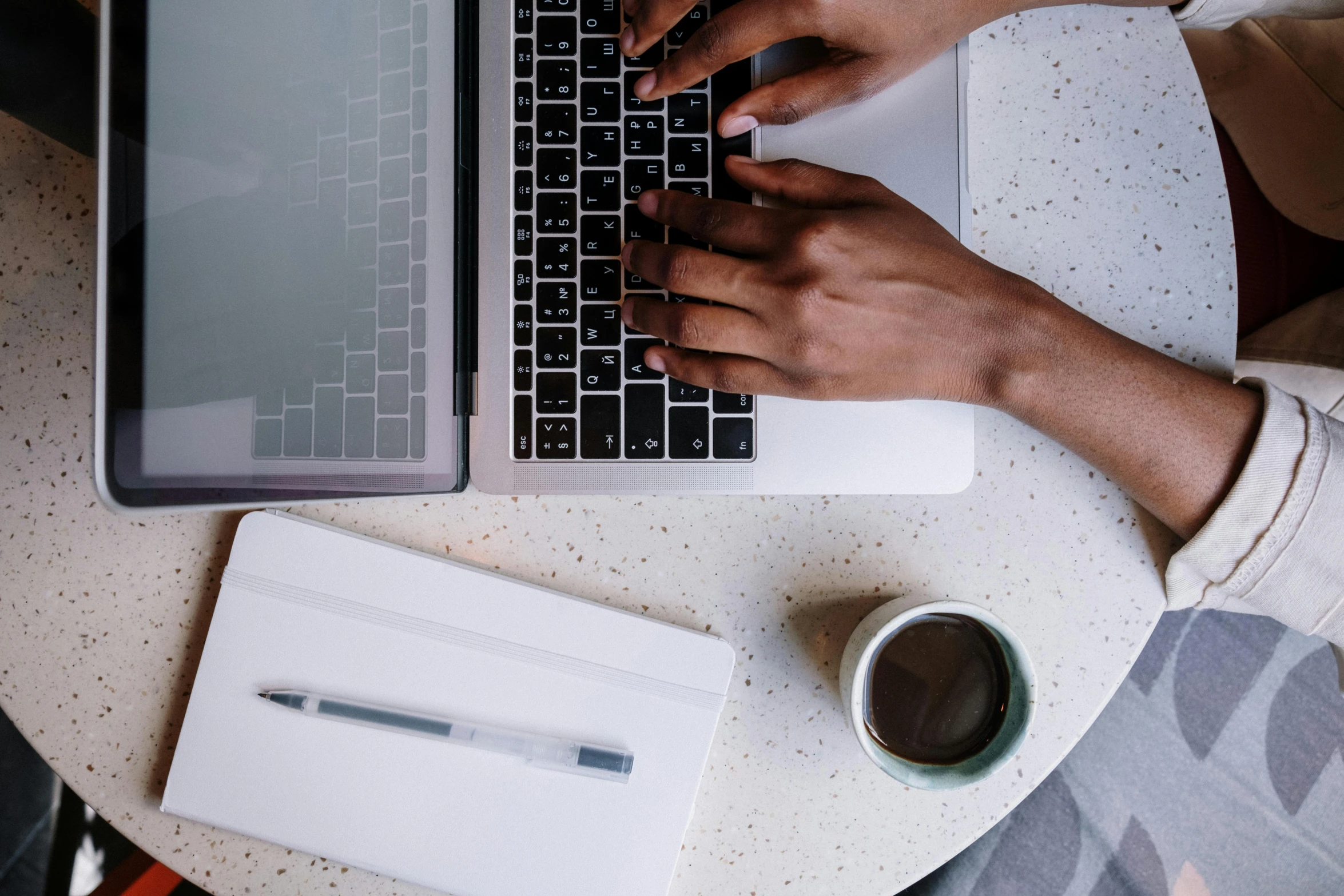 a person typing on a laptop on a table, by Carey Morris, trending on unsplash, flatlay, multiple stories, afro tech, table in front with a cup