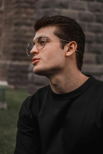 a man wearing glasses sitting on a bench, inspired by Ion Andreescu, trending on pexels, renaissance, round jawline, joe keery, professional profile picture, wearing a black sweater
