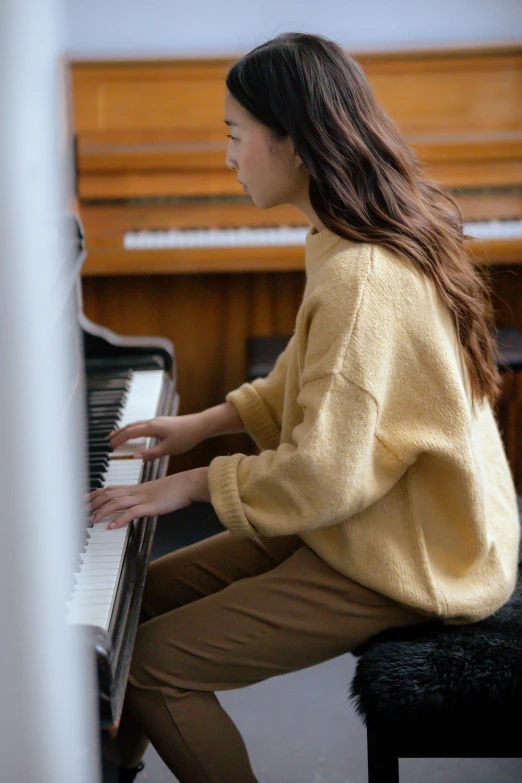 a woman in a yellow sweater playing a piano, trending on pexels, wearing a cardigan, ignant, soft texture, 4l