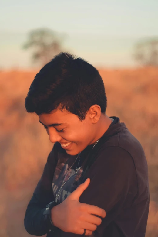 a young man standing in the middle of a field, by Briana Mora, pexels contest winner, warm and gentle smile, teen boy, profile pic, indian