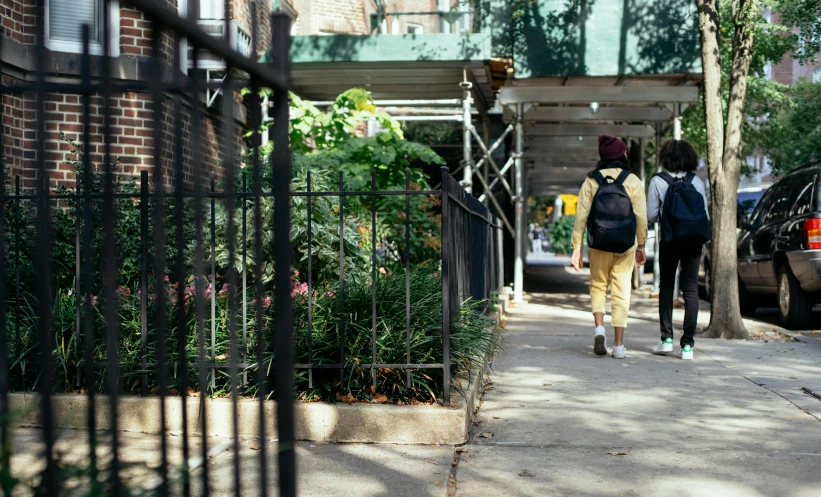 a couple of people walking down a sidewalk, unsplash, ashcan school, overgrown with plants, a woman walking, ignant, parks and public space