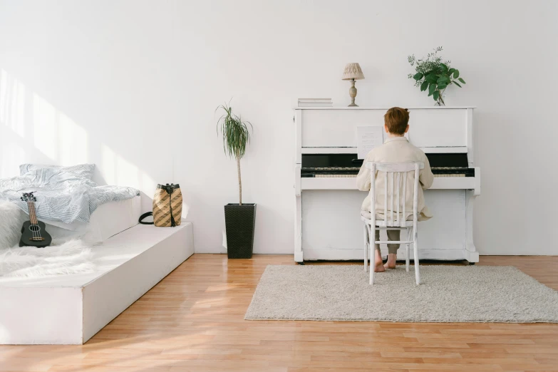 a woman sitting at a piano in a living room, inspired by Wilhelm Hammershøi, pexels contest winner, postminimalism, white space in middle, white bed, music being played, profile image