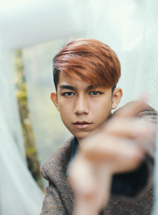 a close up of a person holding a remote, a picture, inspired by Ryan Yee, trending on pexels, sumatraism, undercut hairstyle, caramel. rugged, portrait of forest gog, cute young man