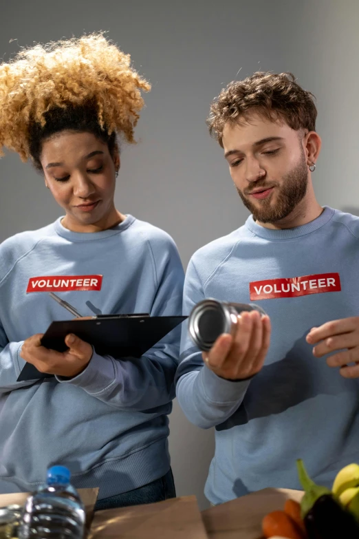 a couple of people that are standing in front of a table, shutterstock contest winner, graffiti, wearing a light blue shirt, holding a tin can, academic clothing, thumbnail