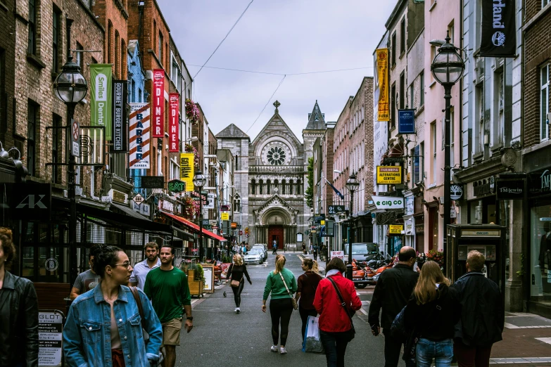 a group of people walking down a street next to tall buildings, irish, 🚿🗝📝, a busy arcade, christian saint