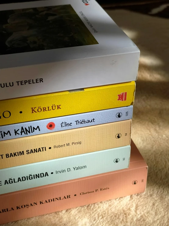 a stack of books sitting on top of a table, poster art, inspired by Oluf Høst, instagram, hyperrealism, mixture turkish and russian, yellow colours, kuntilanak on bayan tree, zoomed in