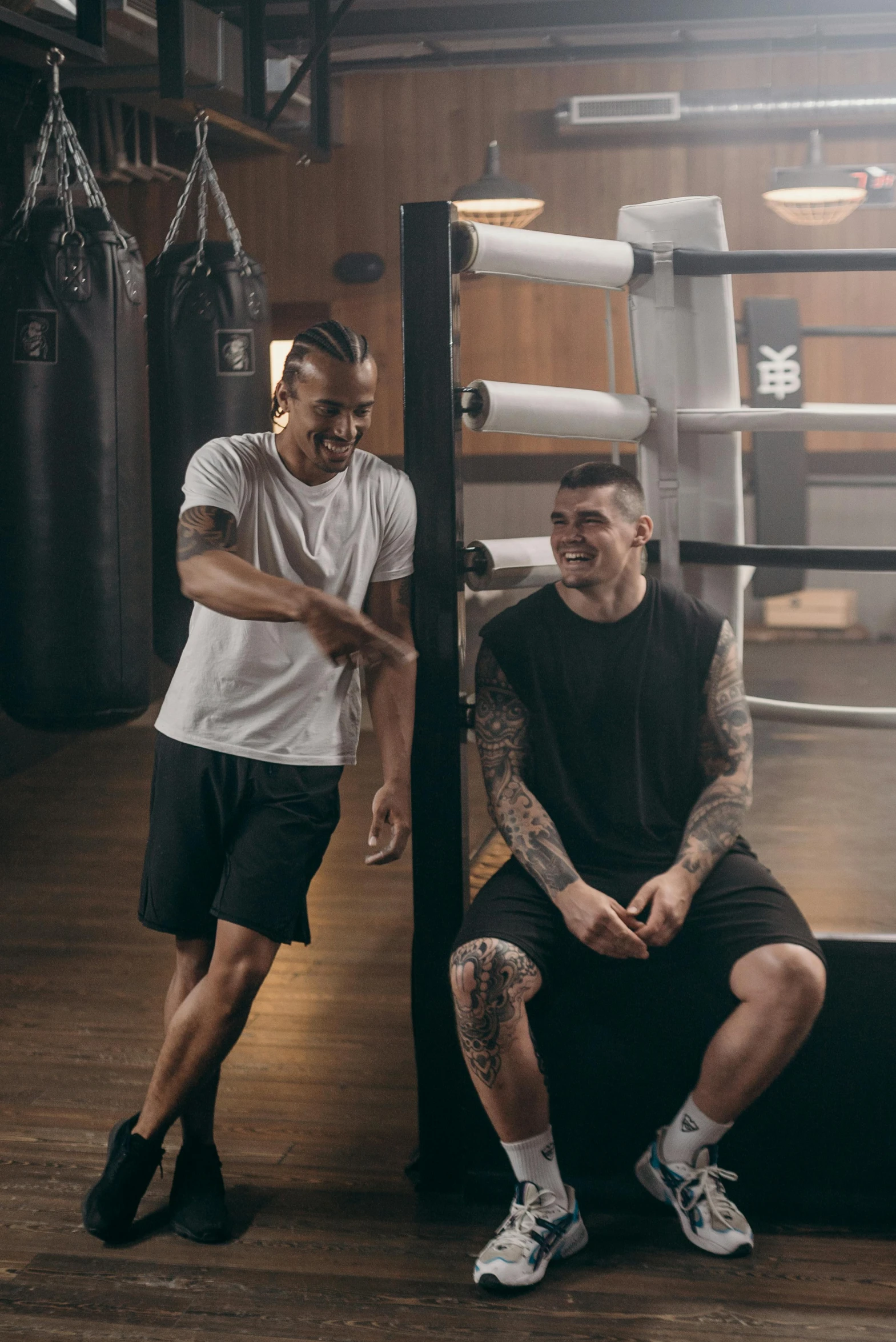 two men sitting next to each other in a boxing ring, by Austin English, working out, tattooed, smiling at each other, ad image