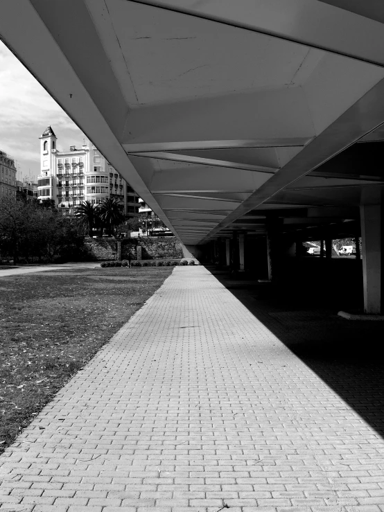 a black and white photo of a walkway, inspired by Vivian Maier, unsplash, monorail, in a square, iphone photo, view from ground