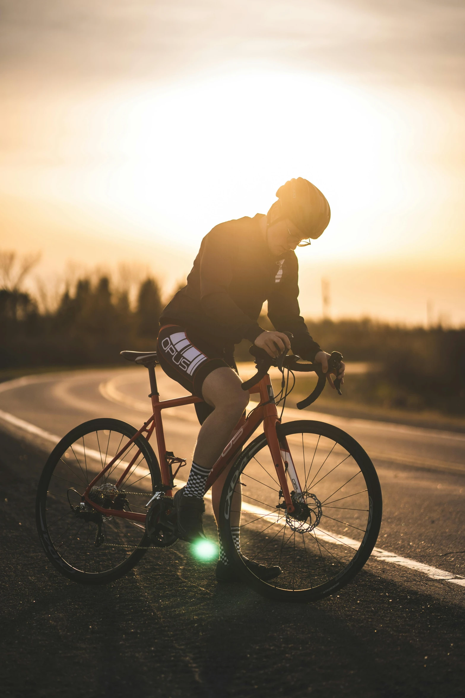 a man riding a bike on the side of a road, during a sunset, profile image, sports photo