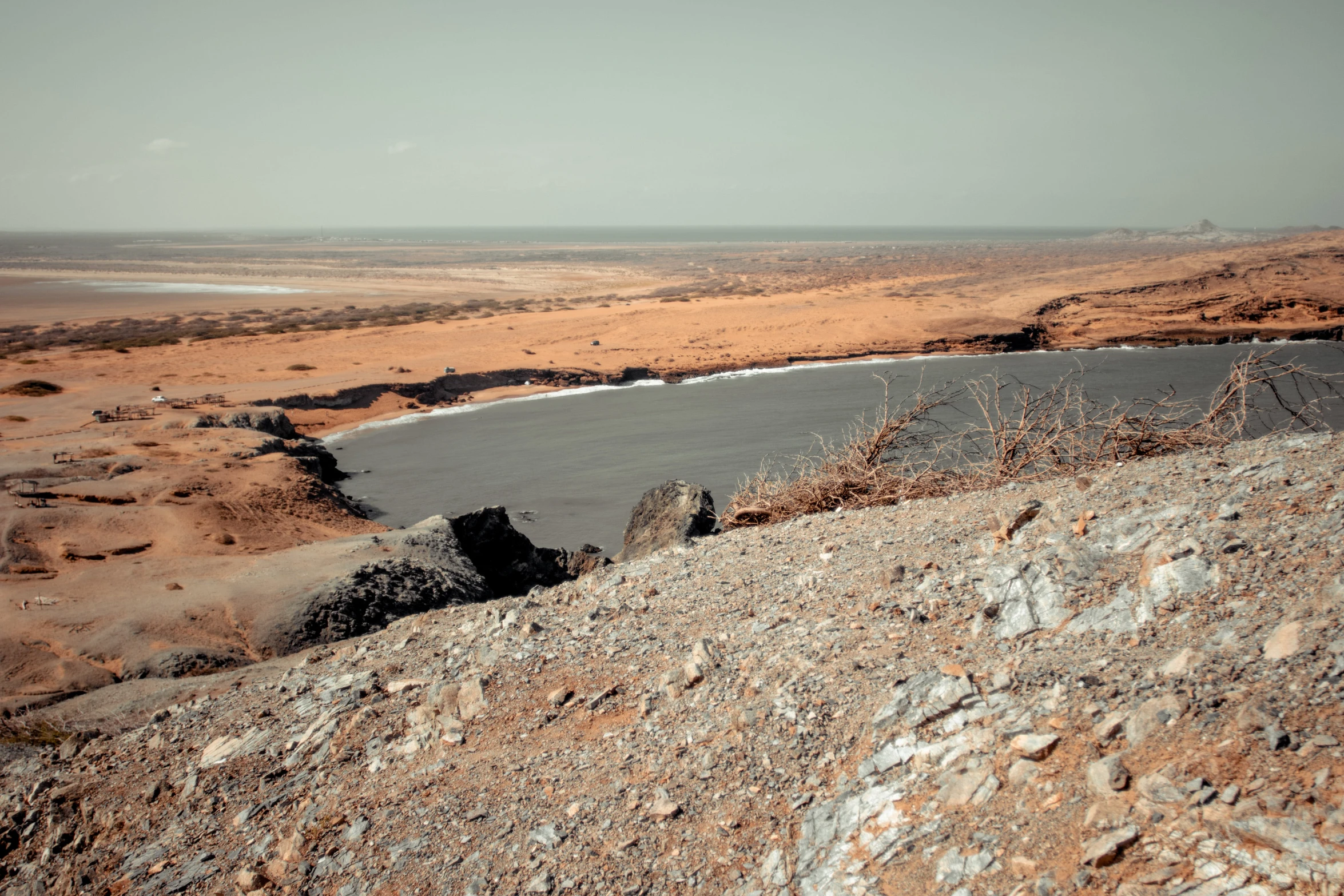 a large body of water sitting on top of a rocky hillside, a colorized photo, pexels contest winner, les nabis, somalia, standing on a martian landscape, landscape photo-imagery, grey