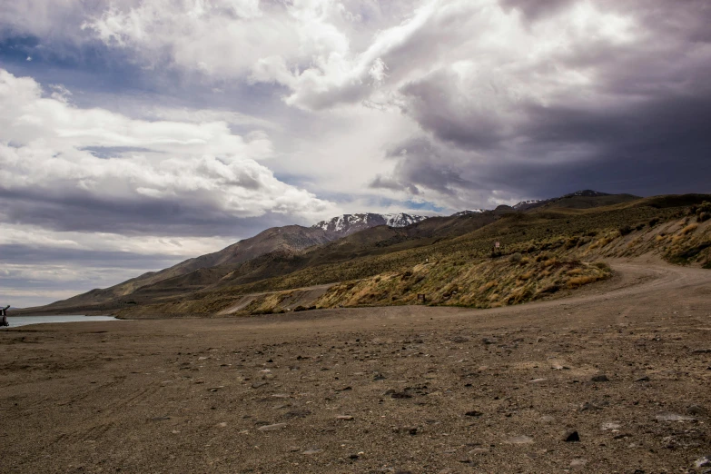 a motorcycle parked on the side of a dirt road, by Muggur, unsplash, hurufiyya, glacier landscape, ceremonial clouds, gravels around, mid shot photo