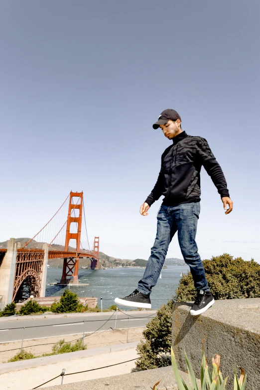 a man flying through the air while riding a skateboard, by Sven Erixson, happening, golden gate, wearing jeans and a black hoodie, standing on rock, looking off into the distance