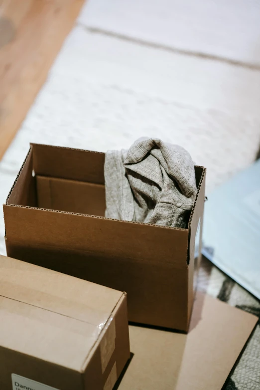 a couple of boxes sitting on top of a wooden floor, brown clothes, opening, still in package