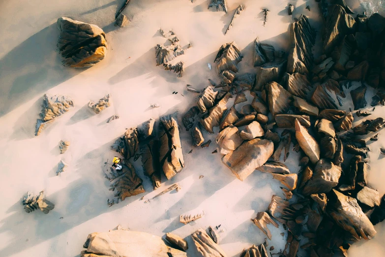 a pile of wood sitting on top of a snow covered ground, a tilt shift photo, by Lee Loughridge, unsplash contest winner, tessellated planes of rock, australian beach, aerial view of an ancient land, sand mists