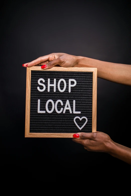 a woman holding a sign that says shop local, istock, square, high quality picture, paul barson