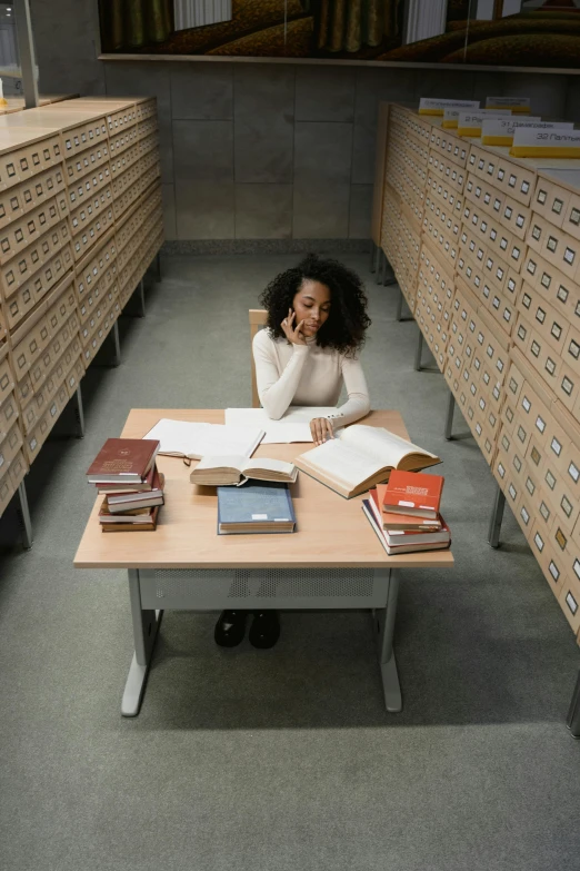 a woman sitting at a desk in a library, an album cover, pexels, research complex, ashteroth, spiral shelves full of books, photograph credit: ap