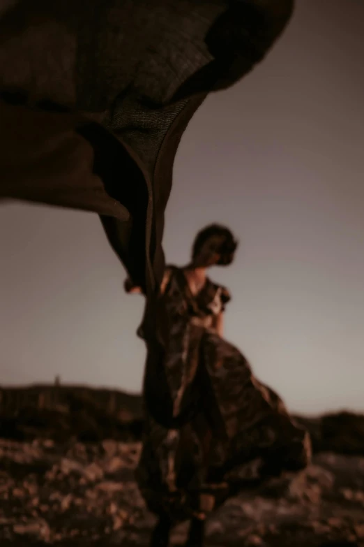 a woman that is standing in the dirt, by Alexis Grimou, unsplash, draped in flowing fabric, dusk, low quality photo, low detailed