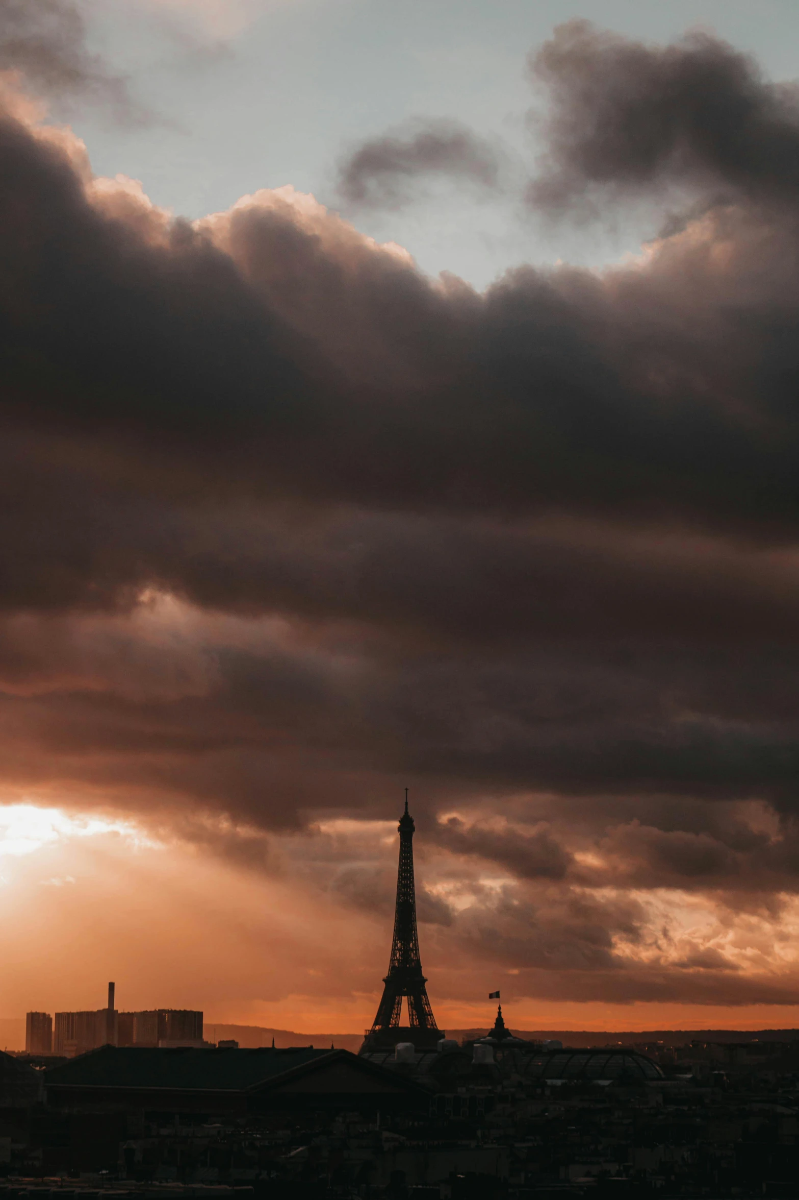 the eiffel tower is silhouetted against a cloudy sky, unsplash contest winner, burning clouds, low quality photo, brown, cinematic shot ar 9:16 -n 6 -g