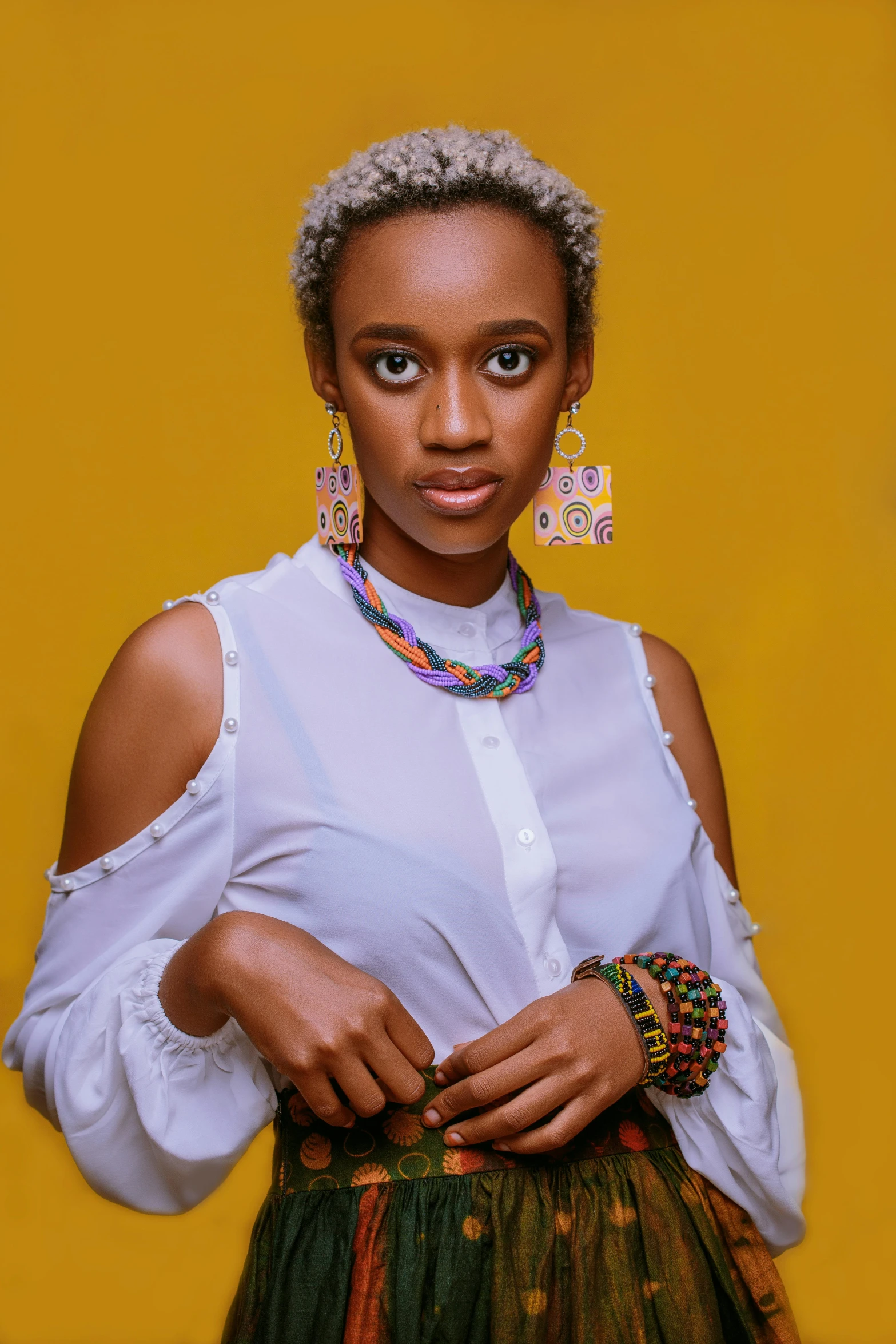 a woman in a white shirt and green skirt, an album cover, inspired by Chinwe Chukwuogo-Roy, photo of a hand jewellery model, wearing yellow croptop, ( ( dark skin ) ), fashion shoot 8k