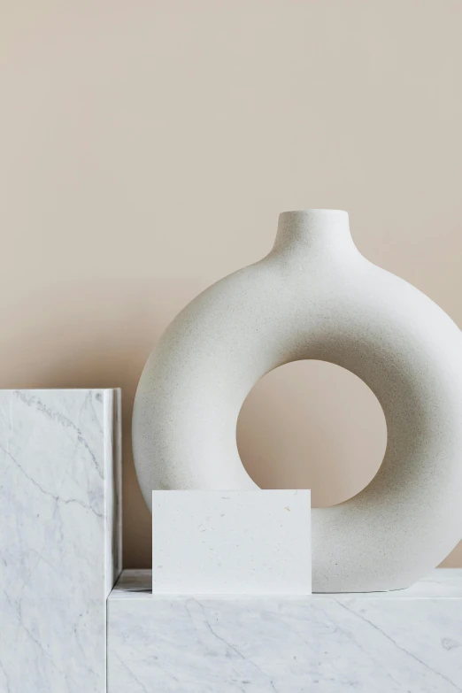 a white vase sitting on top of a marble block, beige color scheme, monochromatic colour palette, stylishly designed background, soft vinyl